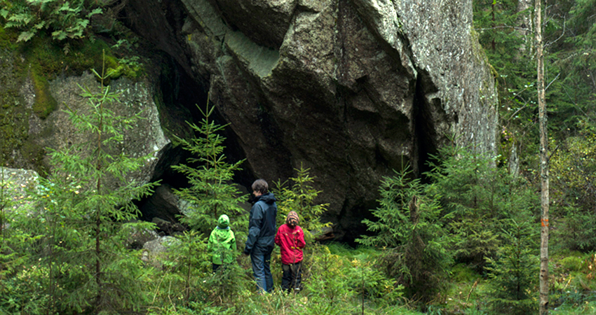 En familj framför ett bergsblock.