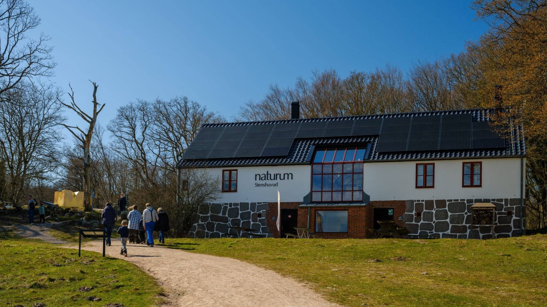 En grusgång leder fram till Naturum Stenshuvud i Stenshuvuds nationalpark, där besökare står utanför.