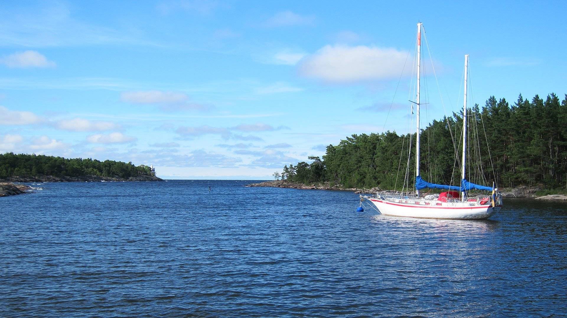 Segelbåt ligger för ankar i Malbergshamn, en smal havsvik omgiven av skog. Djurö Nationalpark, Västra Götaland, Sverige.