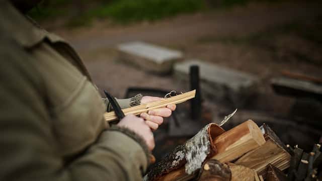 Kvinna tänder brasa på utflykt i naturen, naturreservat i Kungälv.