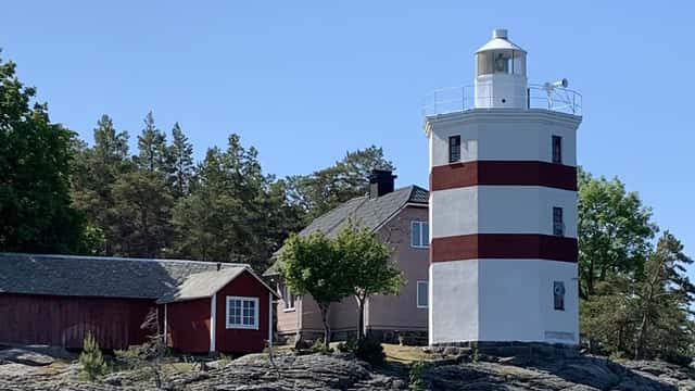 Fyren på Djurö sett från vattnet. Vid sidan av fyren syns fyrvaktarbostaden.