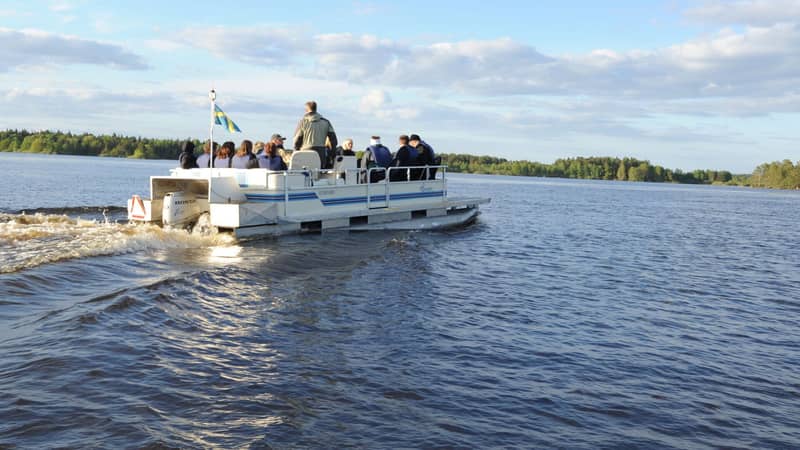 Öppen pontonbåt med tolv passagerare kör på Dalälven.