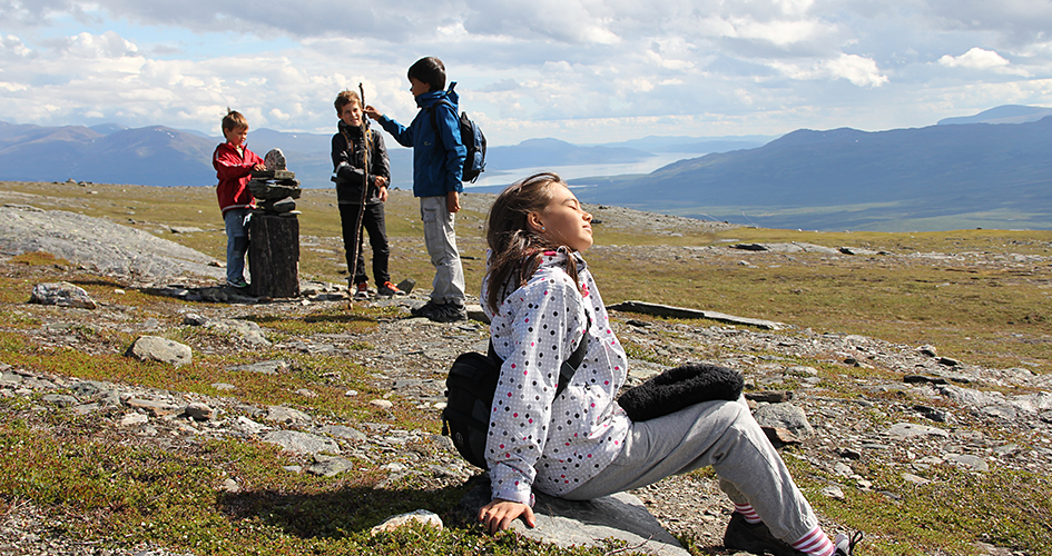 A group of children on a mountain moor, in the background mountain landscape.