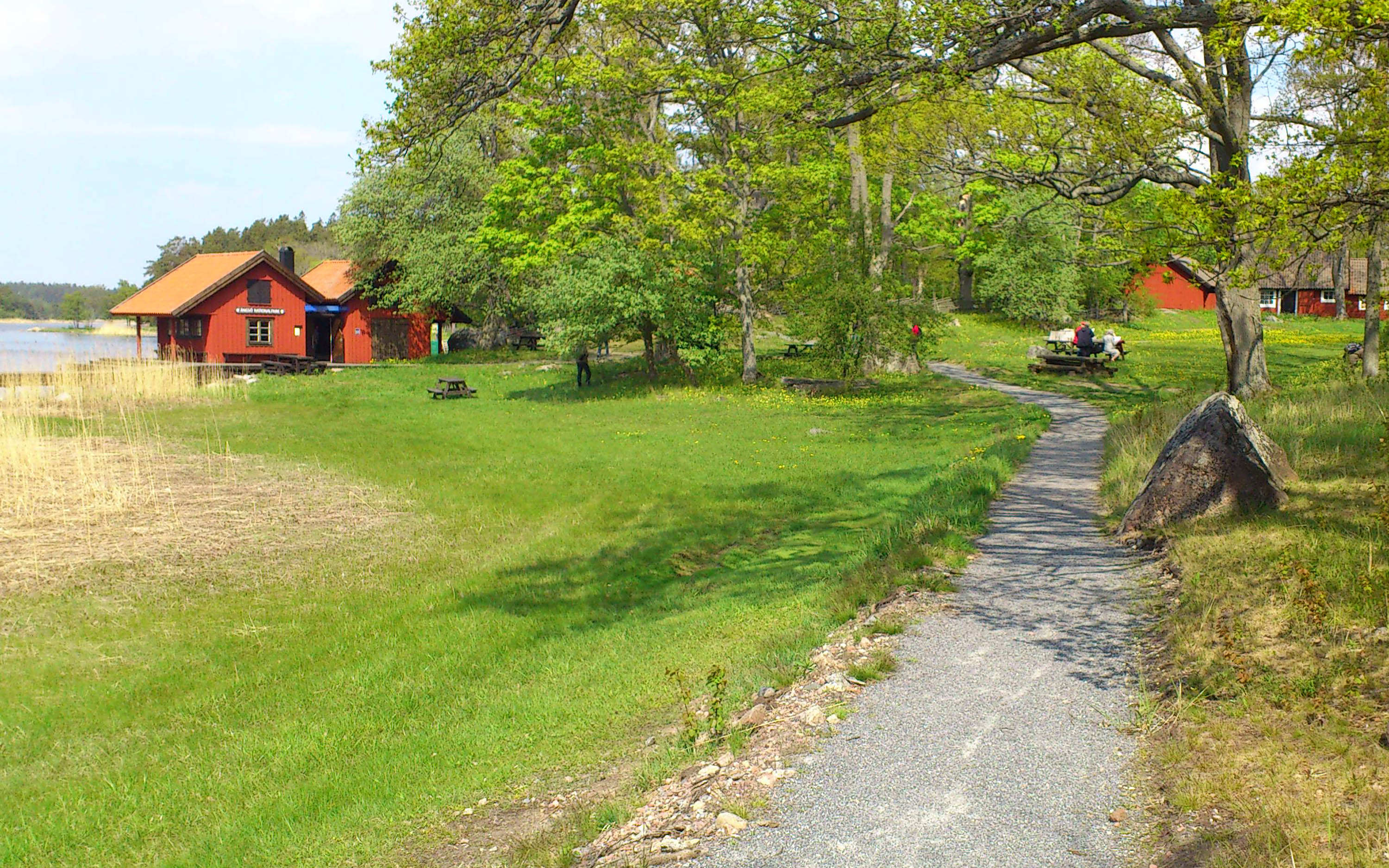 Stora ekar och faluröda hamnstugor möter besökare i Ängsö nationalpark