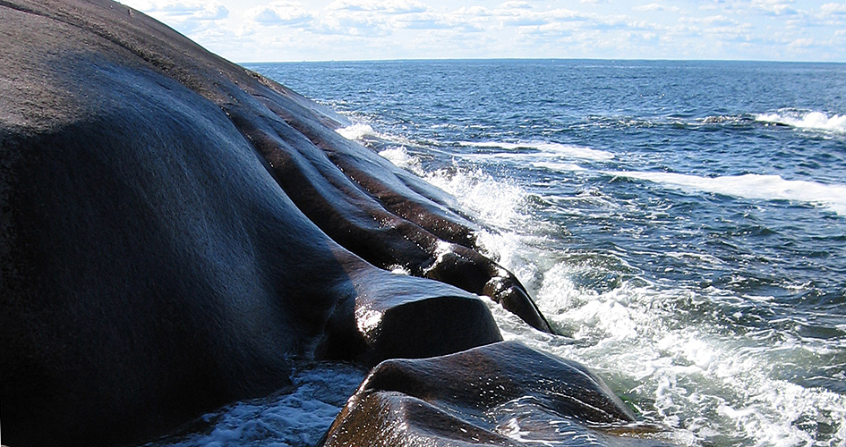 Waves hit smooth rocks.