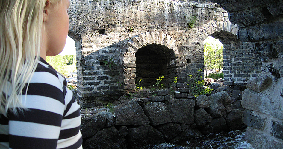 A child in profile looks down on the mill ruin.