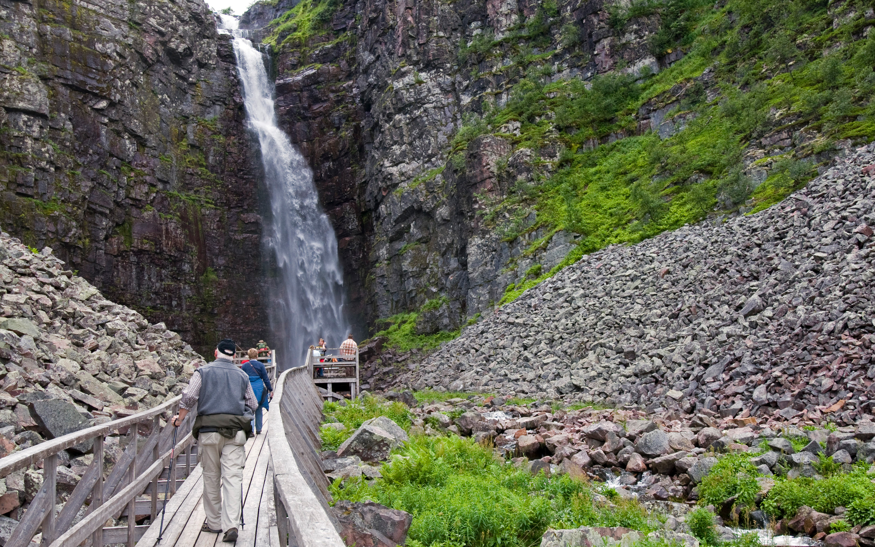 Personer på träspång med Njupeskärs vattenfall i bakgrunden