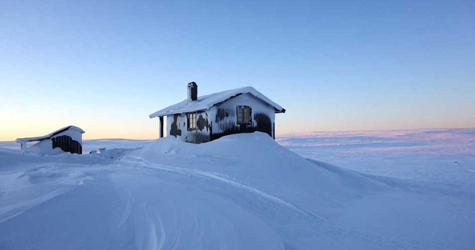 En snötäckt stuga i vinterlandskap.