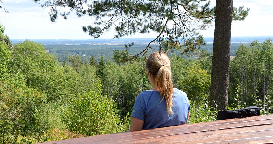 Person sitter vid bord och ser ut över vidsträckt landskap