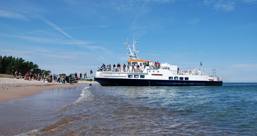 Människor går på ett passagerarfartyg som kört in till stranden.