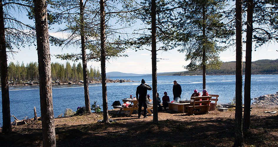 Ett sällskap rastar vid rastbord vid vatteni Muddus/Muttos nationalpark