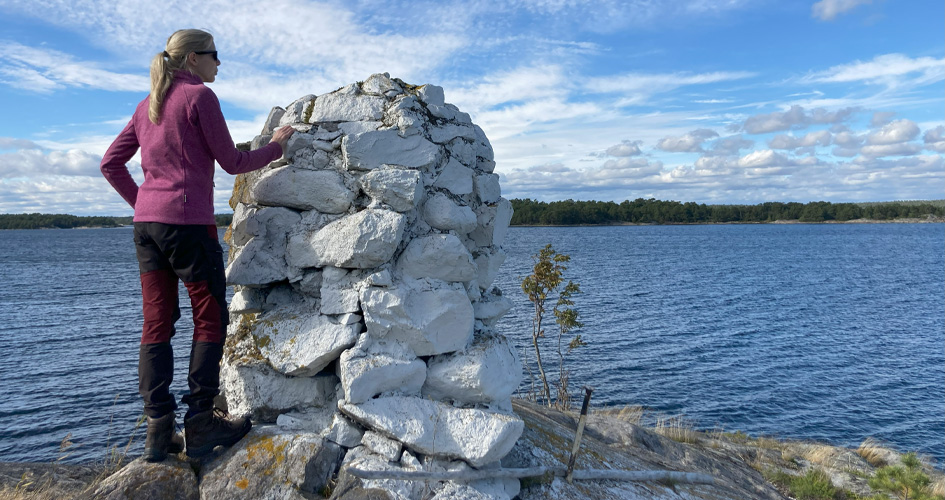 Utsikt från Kumlet på Söderö Person står på ett berg vid et kummel och tittar ut över vattnet och öarna runt om.