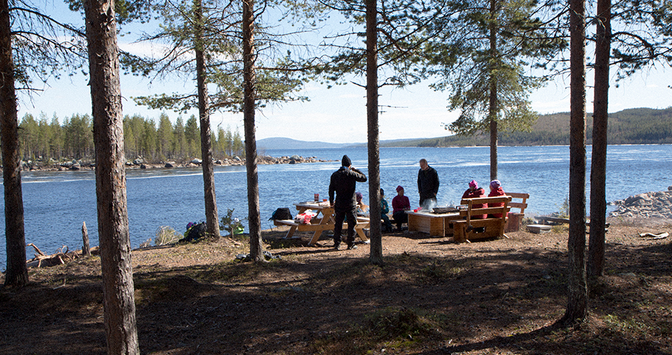 Ett sällskap tar en paus vid en rastplats framför en sjö.
