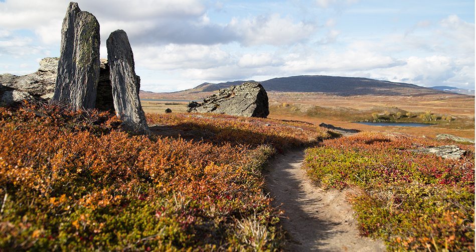 Stig bredvid stenformation med storslagen utsikt bakom. Padjelanta Bajdelannda  nationalpark 