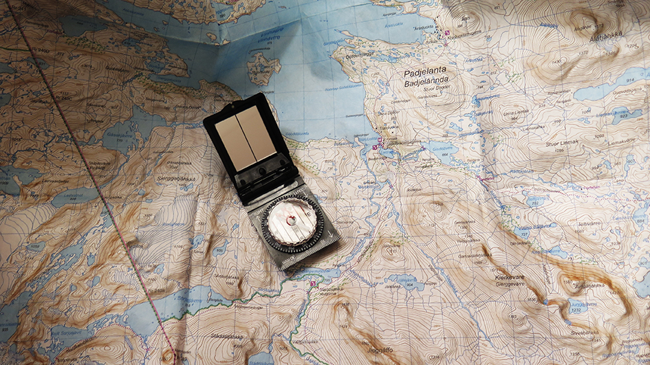 Kompass som ligger i mitten av en uppslagen karta.