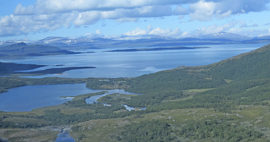 Landskapsvy över Stáloluokta, Badjelannda Padjelanta. En sjö avtecknar sig mot en blå himmel omgivet av fjällandskap.