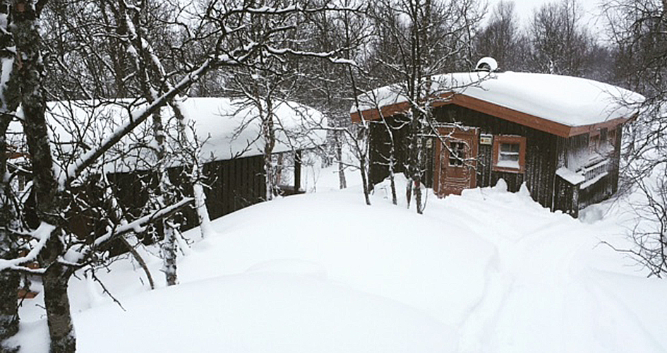 En stuga i ett snöigt landskap.