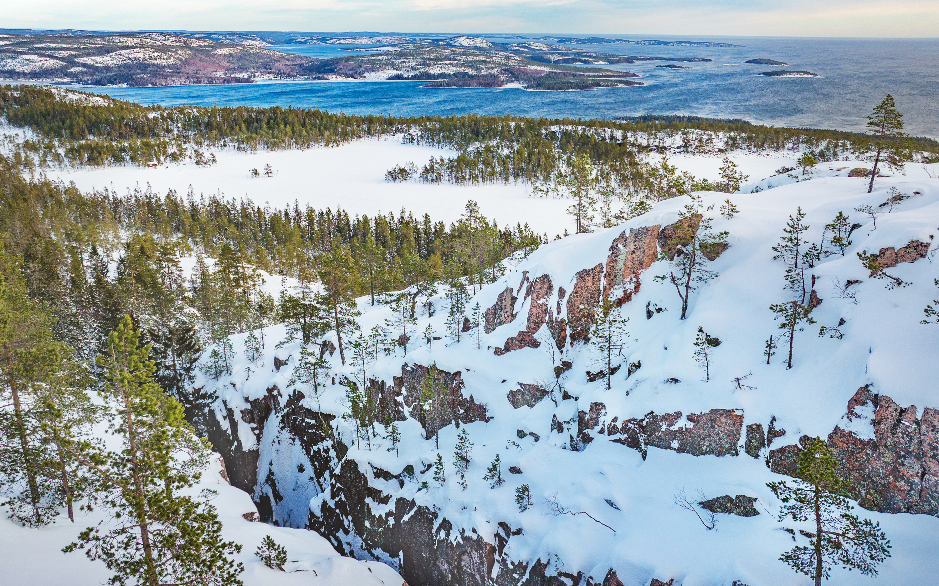 Vy över klippor och skog täckt av snö.