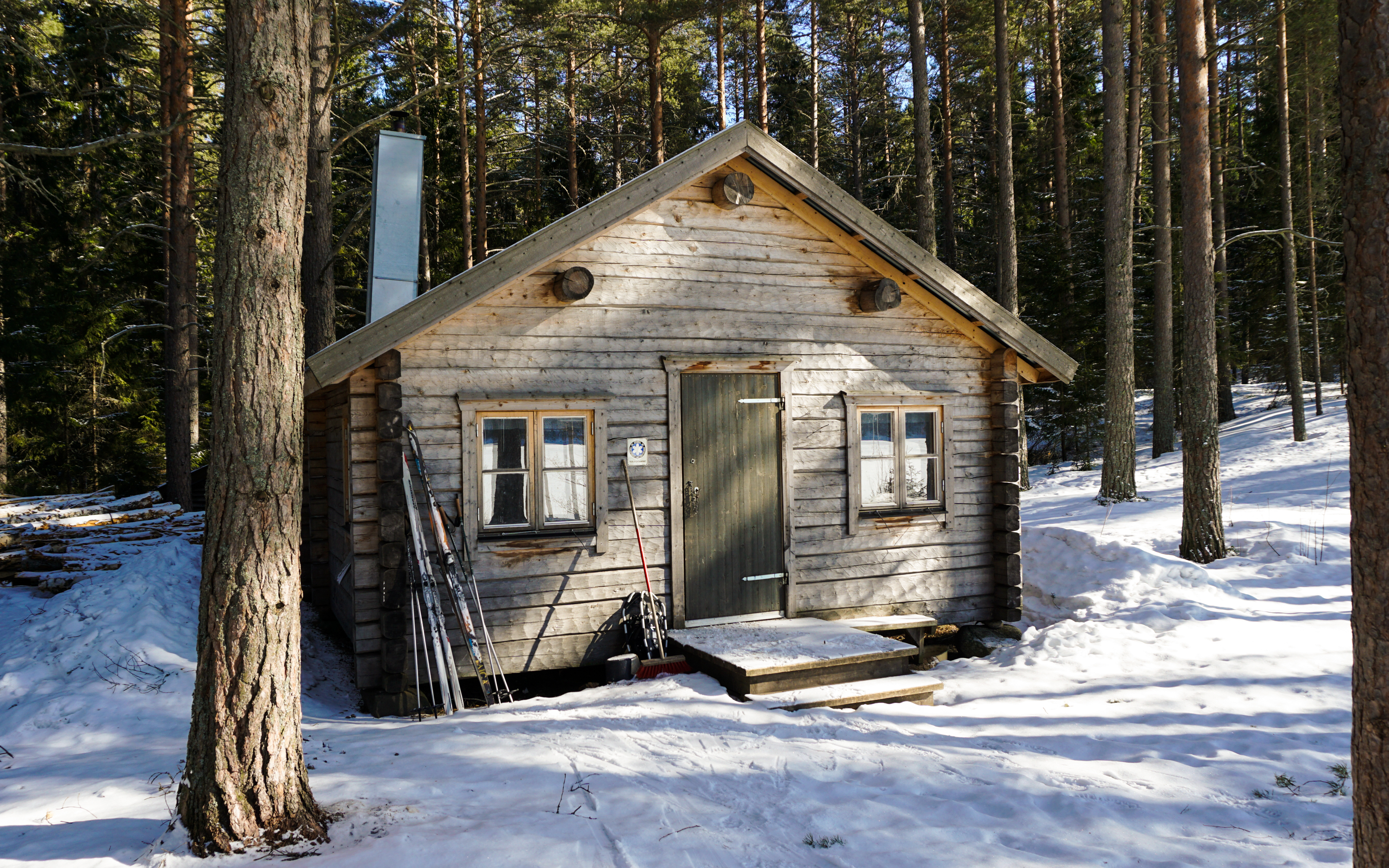 A log-cabin in the woods surrounded with snow.