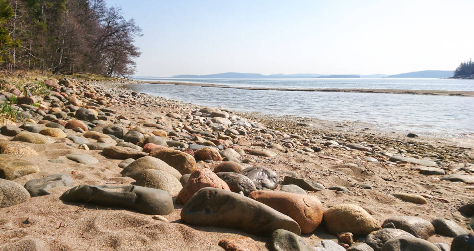 En strand med sand och stenar vid havet.