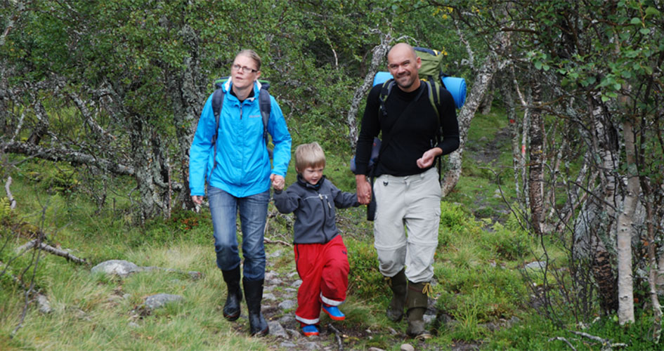 En kvinna och en man går med ett barn emellan sig på en vandringsled.