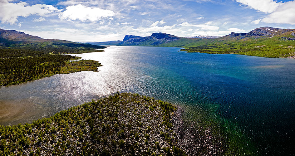 Flygplansvy sommartid, över sjön Langas, fjäll och solig himmel. Stuor Muorkke