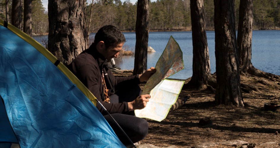 A man is sitting at a rest area with a map in his hand.