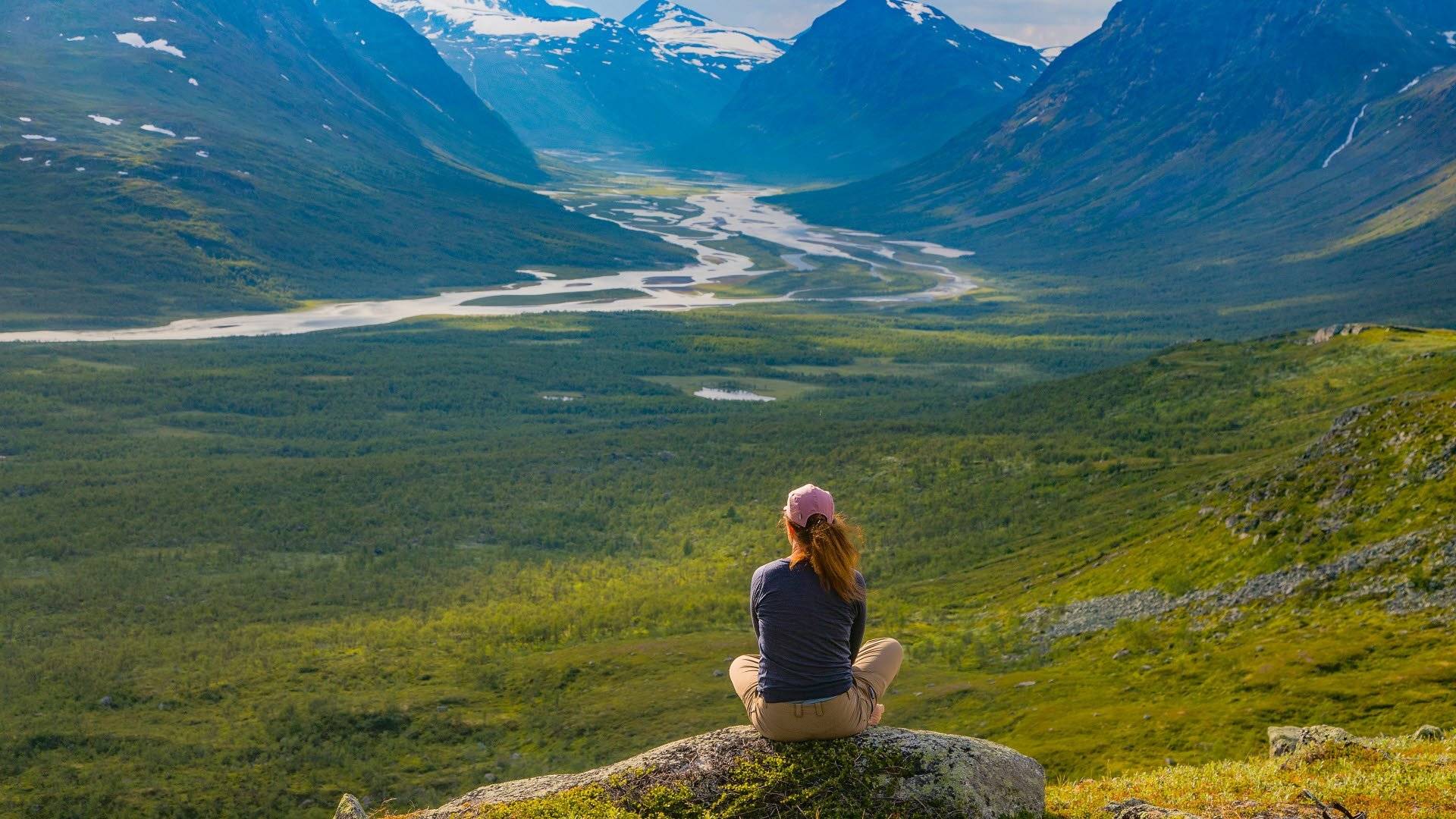 Besökare sitter på sten och ser ut över Rapadalen i Sareks nationalpark.