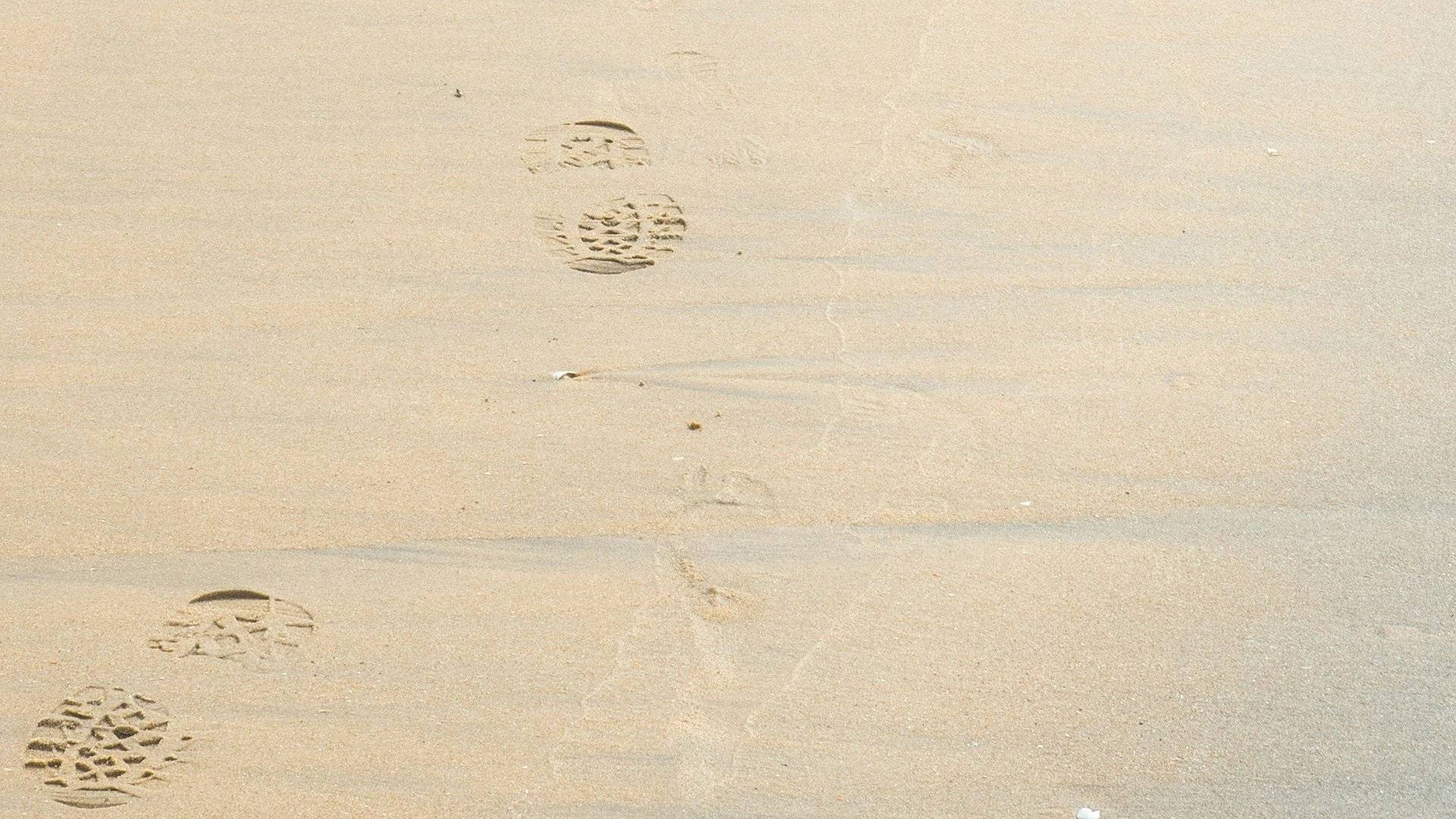 Fotspår i sanden på en sandstrand.