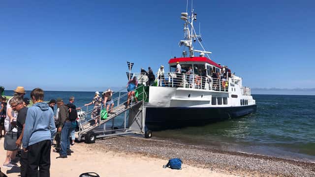 Länsstyrelsen Gotland Färja vid sandstrand med människor på landgången.