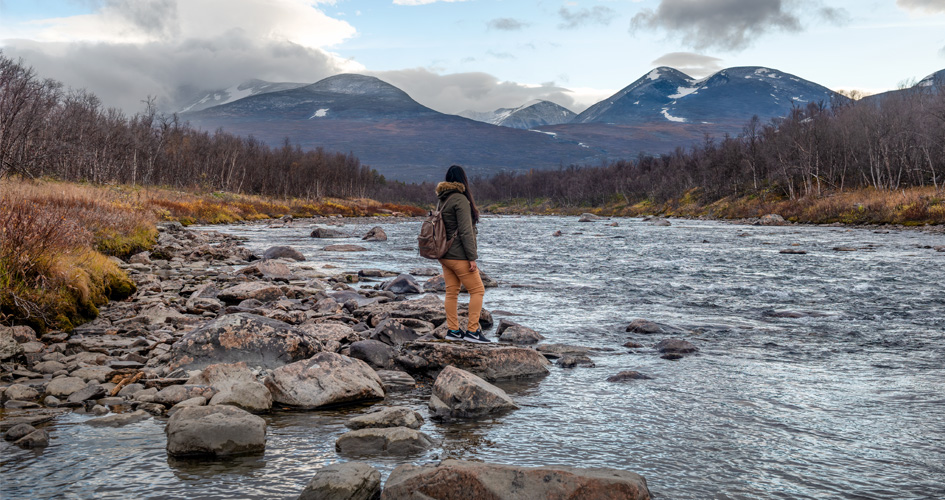 Woman by a stream overlooking mountains in Abisko national park