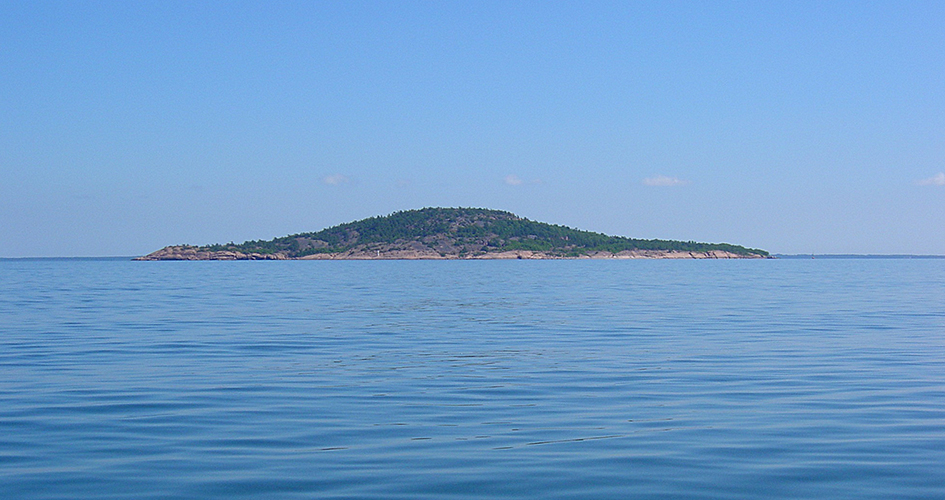Blå Jungfrun National Park photographed from the sea. The water is still and blue.