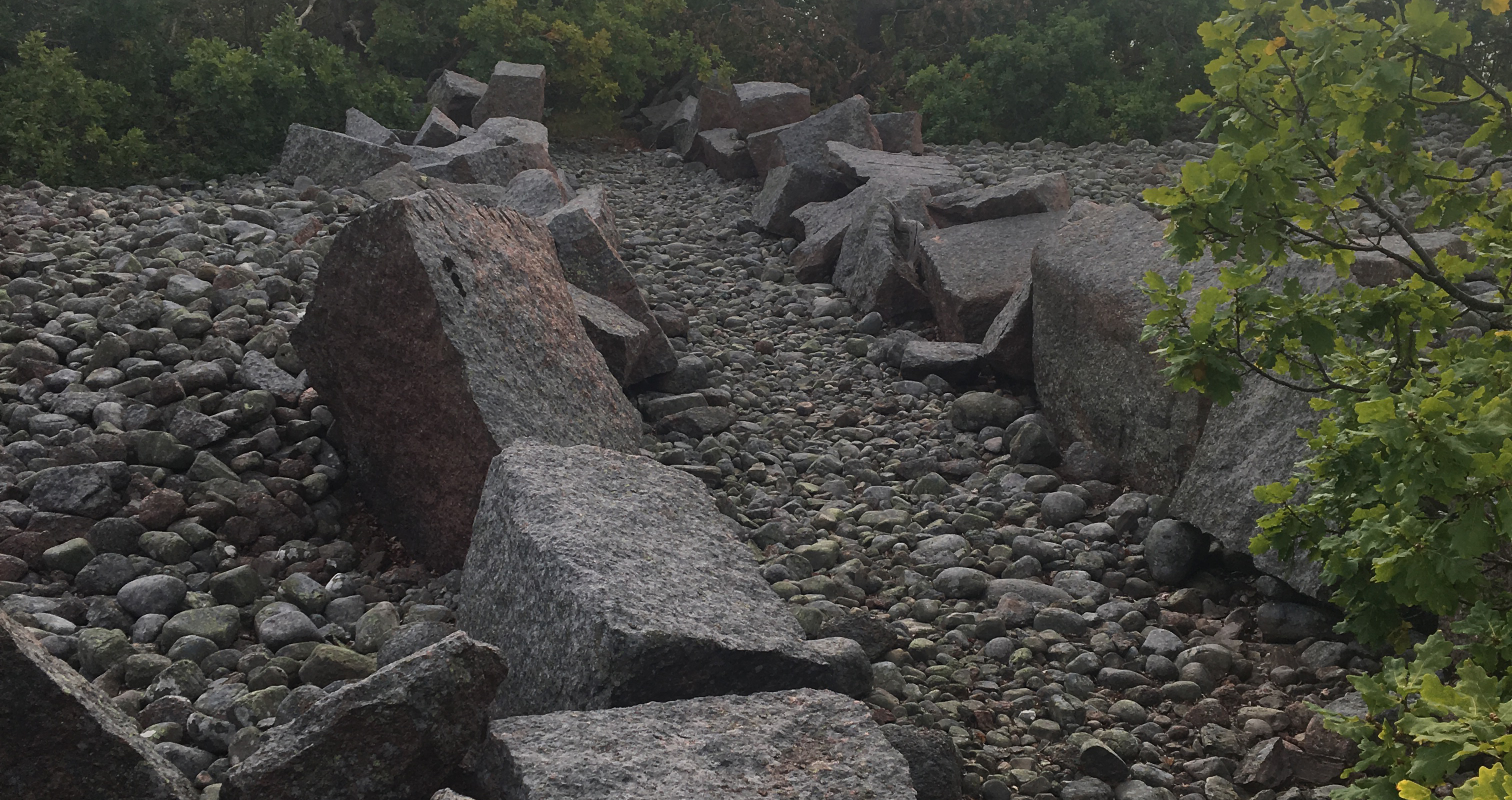 Ett rad med stora kantiga stenblock på ett bädd av mindre stenar.