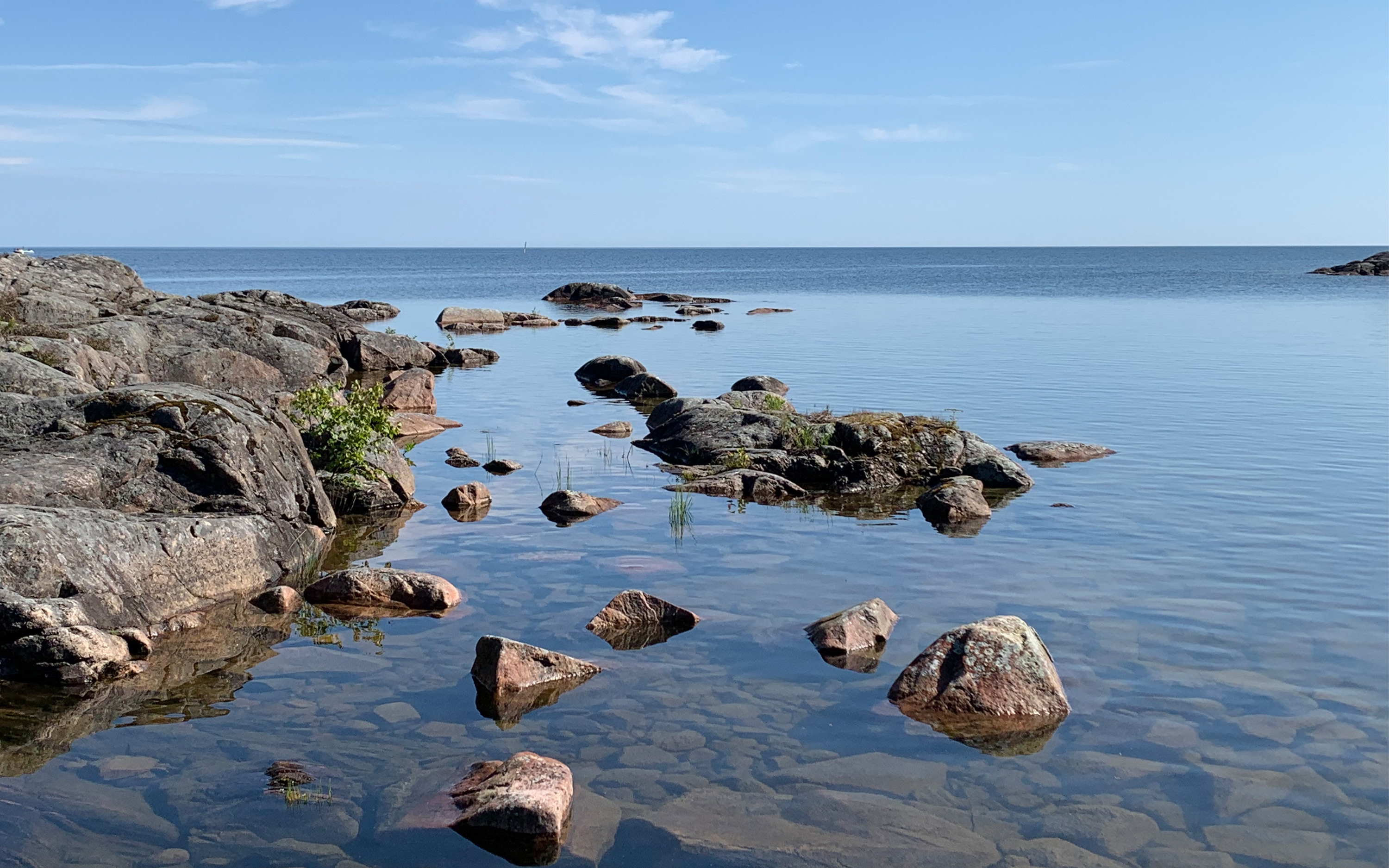 Hav, stenar och kust med blå himmel