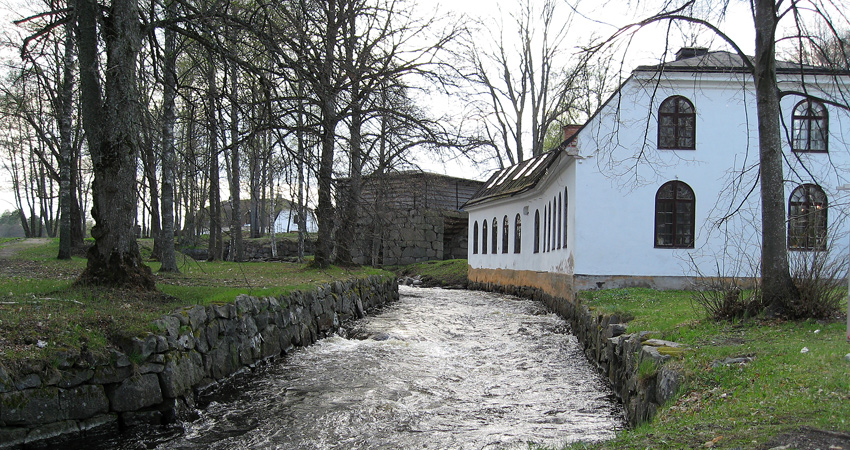Whitewashed building at the edge of a rapids.