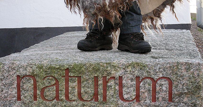 Children's feet stand on a stone with the text naturum.