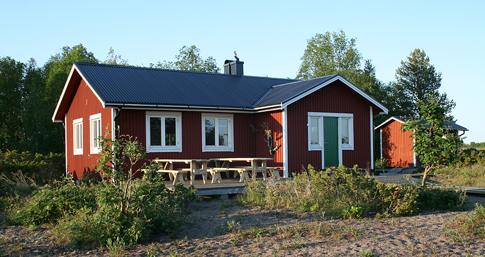 Röd stuga vid stranden.