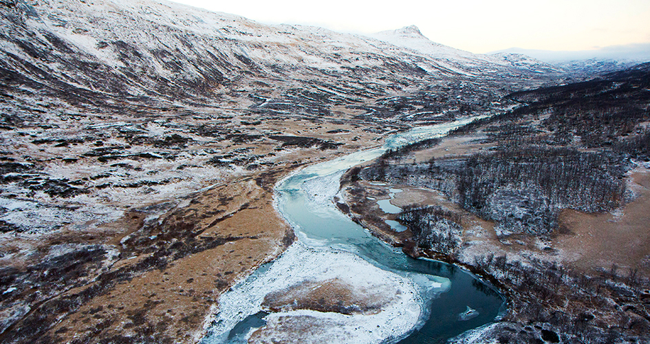 Flygfoto över en fors i det karga fjällandskapet.