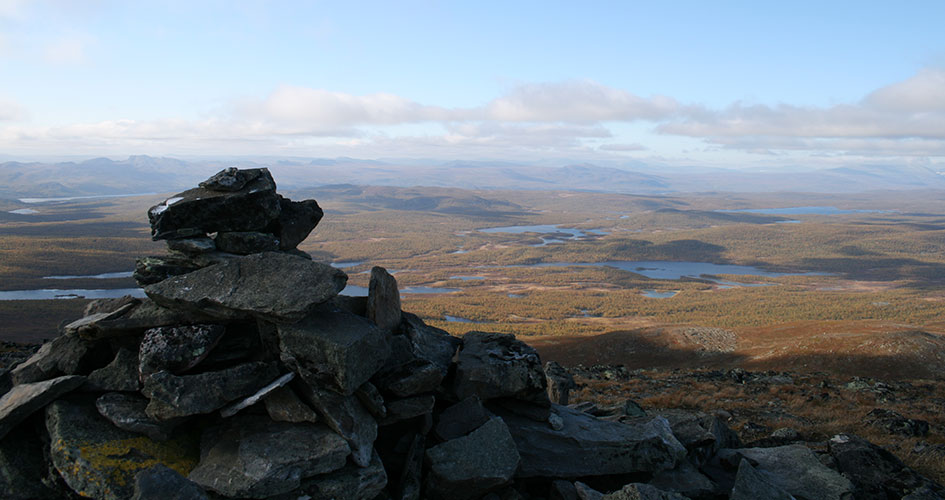 Stenformation med landskapsvy över lågfjäll bakom.