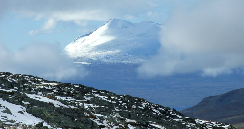 Ett snöklätt fjäll tornar upp sig mot skyn.